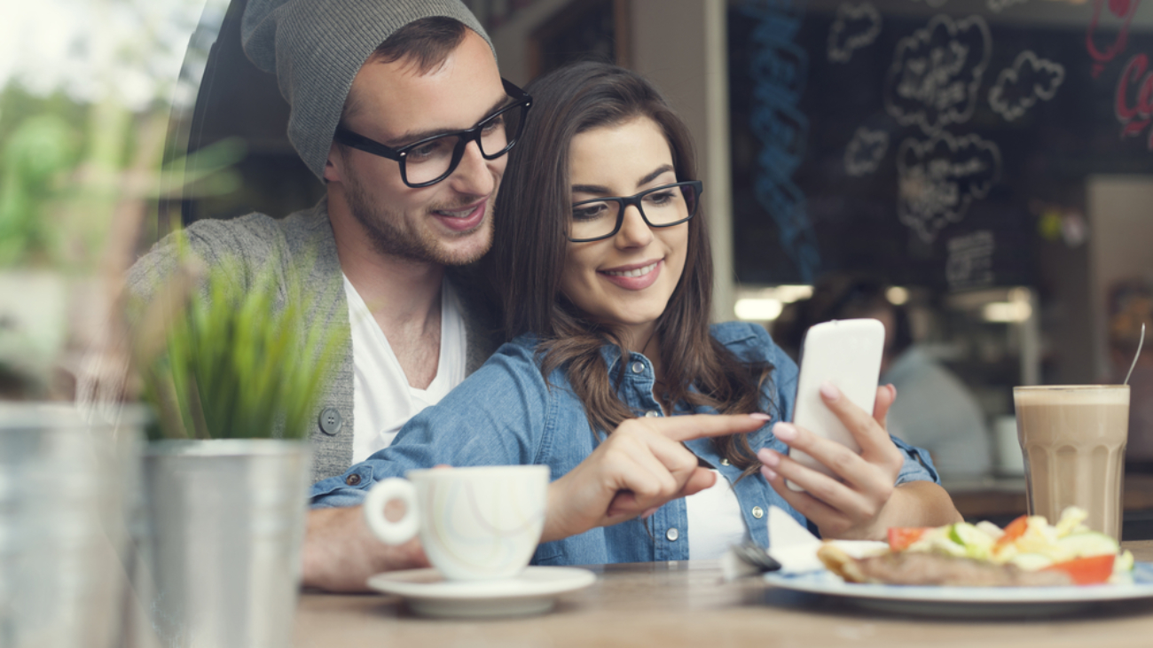 Image of a couple using a mobile device at a cafe